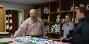 (left to right): Malcolm Mize, assistant plant manager, dyeing and finishing, A&E, explains the company’s color matching process to Miranda Tidwell, materials developer, VF Workwear; and Specialty Designer J. Aaron Needles, Air Force Uniform Office.